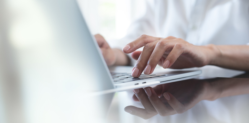 Hands typing on a laptop keyboard