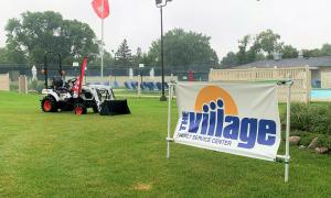 The Village banner is next to a Bobcat loader.